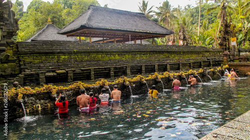 People are doing the ritual purifying bath at Tirta Empul temple, a Hindu Balinese water temple famous for its holy spring water, in Bali, Indonesia.