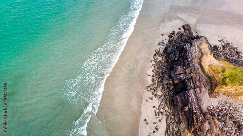 une plage avec rocher et mer verte translucide en vue aérienne