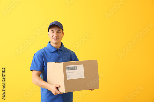 Delivery man with box on color background