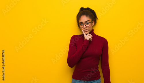 Young black african american girl with blue eyes doubting and confused