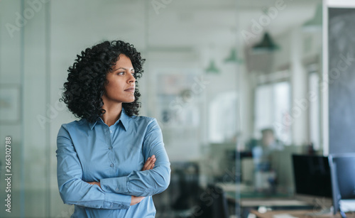 Focused young businesswoman standing alone in an office