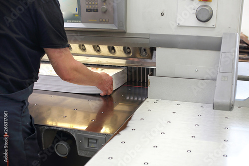 Paper trimming on a guillotine. Work in the printing house.