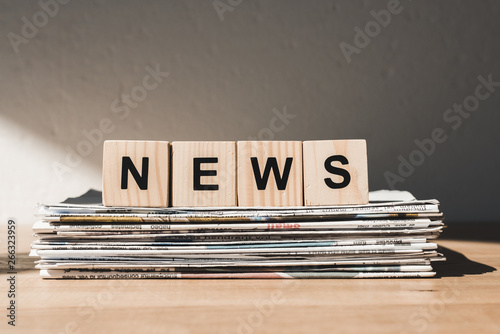 wooden blocks with news lettering on pile of print newspapers