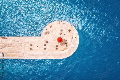 Red lighthouse against blue water of sea. contrast colors. Top aerial view