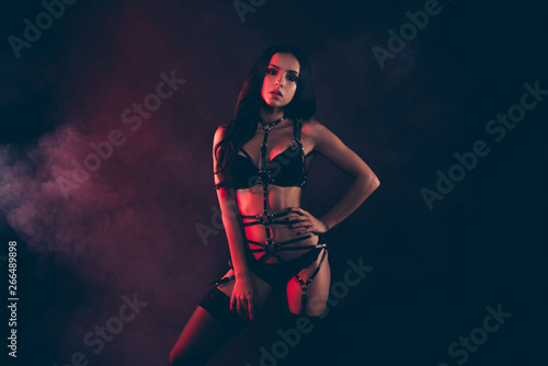 Portrait of nice cool gorgeous adorable attractive sportive perfect thin fit form shape line wavy-haired lady wearing swordbelt teasing enjoying life isolated on black red light background