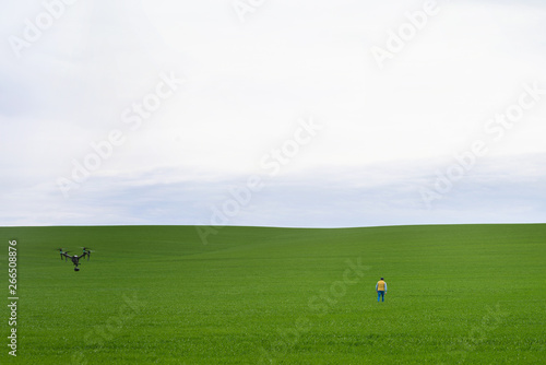 Man goes to the field. Man from behind, a quadrocopter is flying behind him.