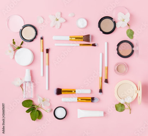 Face care and make up products with spring apple bloom (tonic or lotion, serum, cream, micellar water, cotton pads and makeup brushes) on pink background. Freshness and face care. Copy space