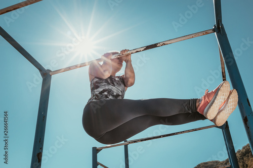 Girl practicing in the morning in the park. Strength practice with metal bars