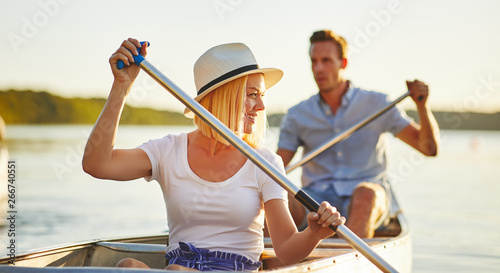 Smiling young couple paddling their canoe on a lake