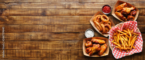 pub appetizers such as chicken wings, onion rings and french fries in panoramic composition