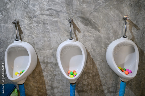 White urinals with colorful mothball in men toilet