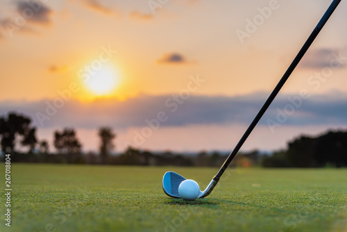 Golfer is putting golf ball on green grass at golf course for hitting to hole with blur background and sunlight ray