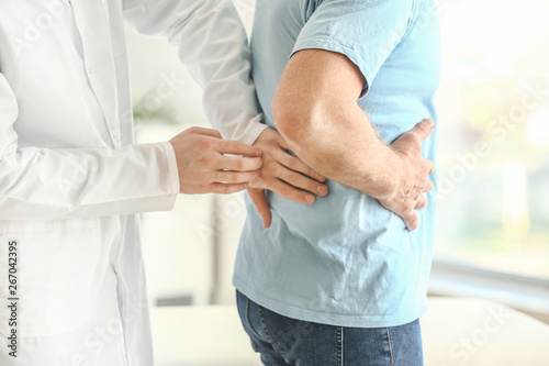 Urologist examining male patient in clinic