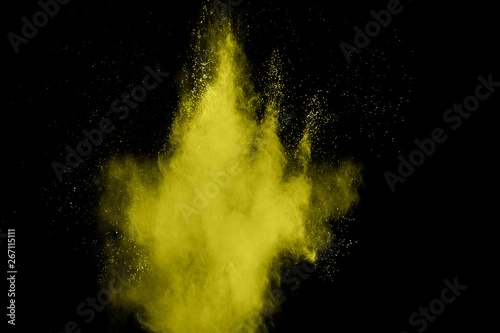 Abstract yellow dust explosion on black background. Freeze motion of yellow powder splash.