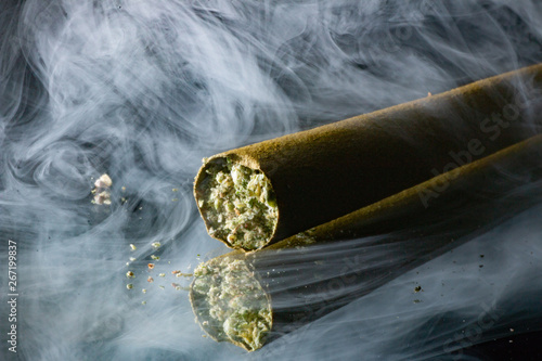 Cannabis blunt sitting on a mirror with smoke in the background. 