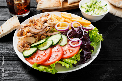 Doner kebab or gyros on a plate with french fries, pita bread and salad.