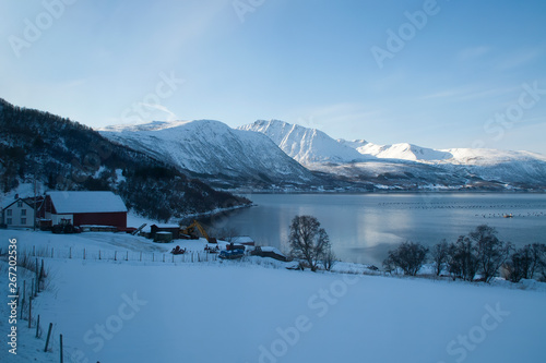 Coastline Norway, view over fish farm with late afternoon sun on mountains in background