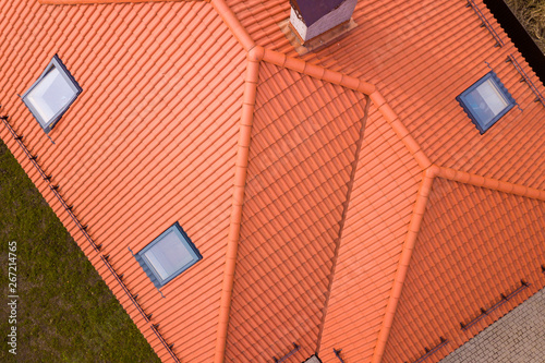 Aerial top view of house metal shingle roof, brick chimneys and small plastic attic windows. Roofing, repair and renovation work.