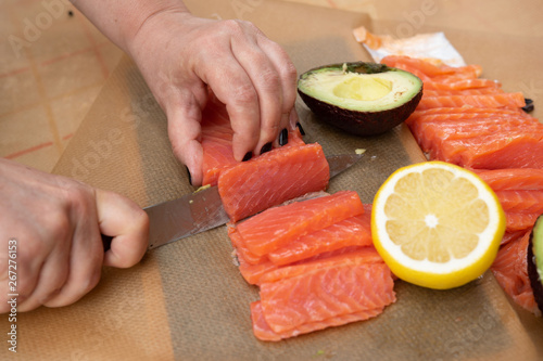 Closeup of Human hands cooking salmon with lemon and avocado in the garden