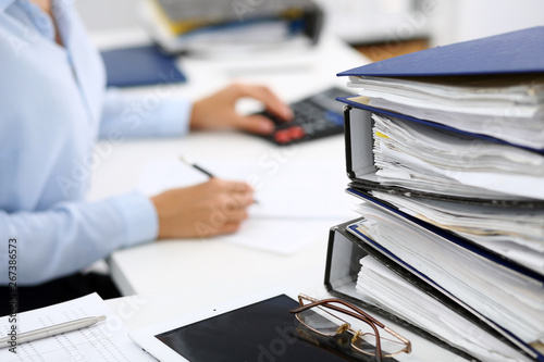 Binders with papers are waiting to be processed by business woman or bookkeeper back in blur. Internal Audit and tax concept