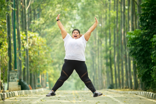 Happy obese woman jumps on the road
