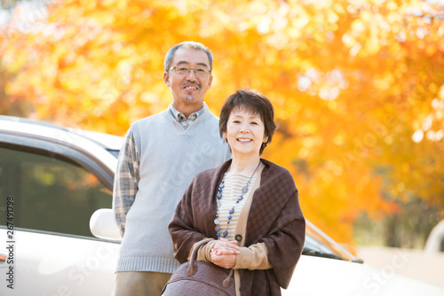 紅葉の前で微笑むシニア夫婦