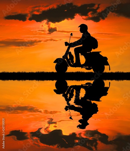 Silhouette biker with his motorbike on blurry blue sky background