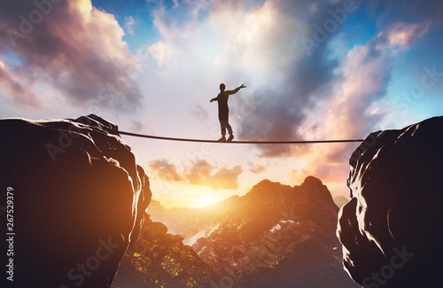 Man walking on rope between two high mountains