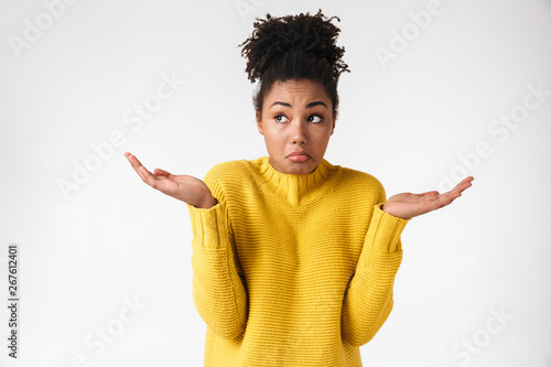 Beautiful young african confused woman posing isolated over white wall background.