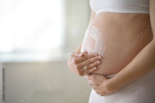 Pregnant woman applying stretch mark removal lotion on her belly