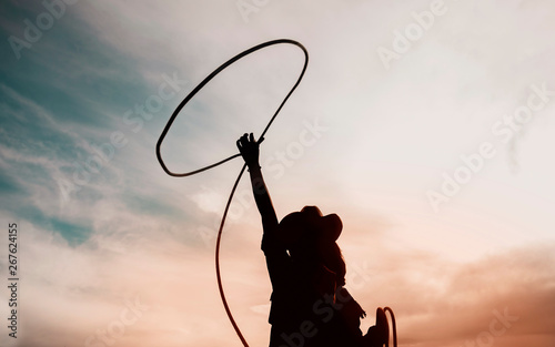 pretty Chinese cowgirl throwing the lasso in a horse paddock