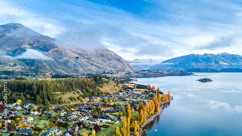 Small town surrounded by yellow autumn trees on a shore of pristine lake with mountains on the background. Wanaka, Otago, South Island, New Zealand
