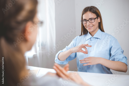 Two women speak sign language. Girls to talk the language of hearing impaired people, the deaf. 