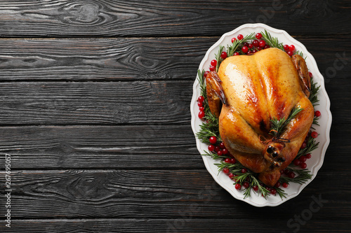 Platter of cooked turkey with garnish on wooden background, top view. Space for text