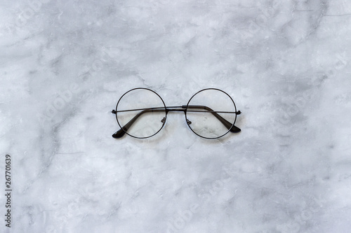 Stylish black round eyeglasses spectacles on marble background. Top view Copy space Minimal style