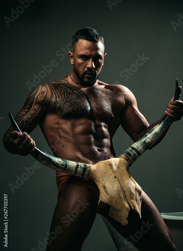 High testosterone level. Strong hispanic man full of testosterone and desire holding skull and horns. Fit latino man showing muscular body and six pack abs, testosterone. Potency and testosterone