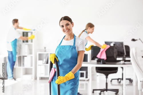 Female janitor with vacuum cleaner in office
