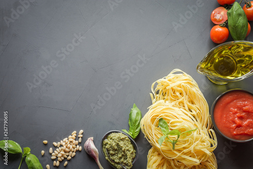 Pasta ingredients for cooking Italian dishes- tagliatelle, tomatoes, basil, olive oil and garlic. Food pattern. Top view with space for text. Horizontal layout.