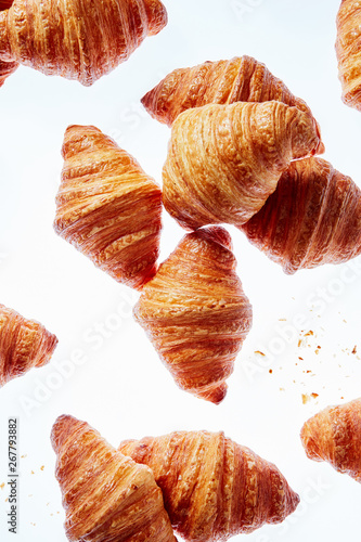 Falling fresh french croissants with crumbs on a light background.