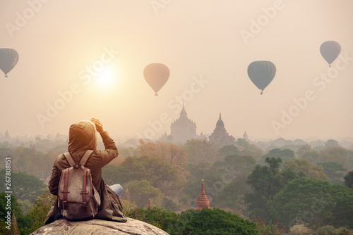 Backpacker traveler in Bagan Mandalay Myanmar and sitting watching balloon air in the morning at Bagan.