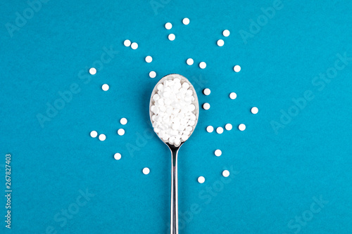 Sugar-replacing tablets with a spoon on a blue background