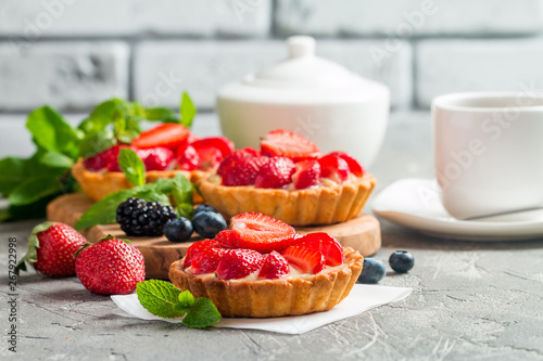 Fresh homemade berrie tarts with blueberries, blackberry and strawberries on gray background