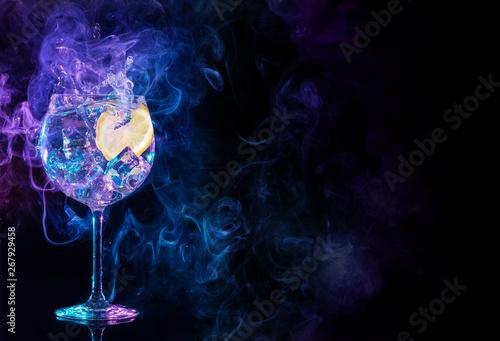 gin tonic cocktail splashing in blue and purple smoky background.