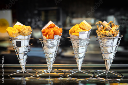 Sea food in cones at counter in small street shop in Spain – snack with mixed takeaway grilled fish and fried seafood – to go delicious roasted octopus, anchovies and calamari ready to eat by tourists