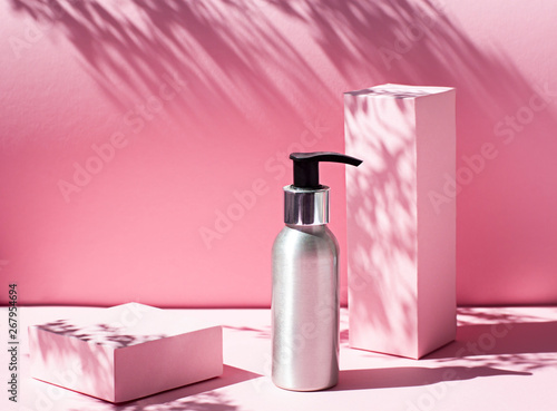 Metallic Cosmetic bottle on the pink background with harsh light. Close up