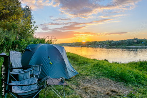 Tourism equipment. Camping tent, tourist chairs in camping by the river