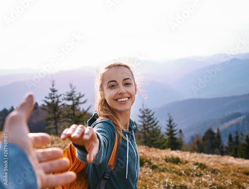 happy attractive woman hiker standing on the mountain slope against background of sunset. Traveling and follow me concept.