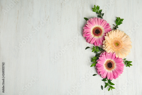 Flat lay composition with beautiful bright gerbera flowers on wooden background. Space for text
