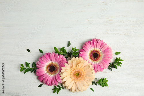 Flat lay composition with beautiful bright gerbera flowers on wooden background, top view. Space for text