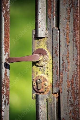 Fragment starej zardzwiałej furtki z klamką i dziurką od klucza